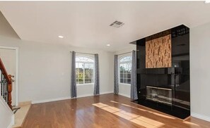 A spacious living room with hardwood flooring, a fireplace, and large windows with curtains. - Spacious 3 bed/bath townhome in marvelous Vegas/Summerlin area with AC and pool. (Las Vegas)
