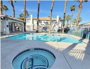 A swimming pool with a hot tub, surrounded by palm trees and a building with a tiled roof. - Spacious 3 bed/bath townhome in marvelous Vegas/Summerlin area with AC and pool. (Las Vegas)