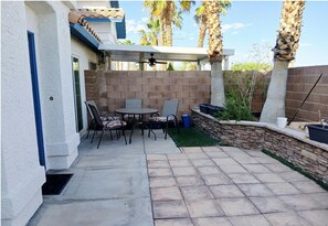 A patio area with a table and chairs, a covered seating area, and a stone wall. - Spacious 3 bed/bath townhome in marvelous Vegas/Summerlin area with AC and pool. (Las Vegas)