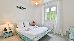 Ein Schlafzimmer mit Bett, Nachttisch, Lampe und Fenster.