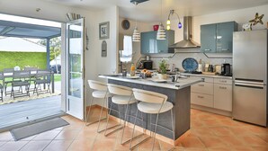 Eine moderne Küche mit Bar, Edelstahlgeräten und Blick ins Freie.