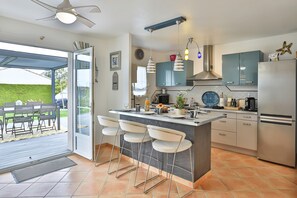 A modern kitchen with a bar area, stainless steel appliances, and a view to the outside. - La Vinière - magnifique villa (Talmont-Saint-Hilaire)