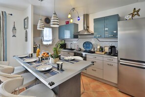 A modern kitchen with a central island, stainless steel appliances, and a large window. - La Vinière - magnifique villa (Talmont-Saint-Hilaire)