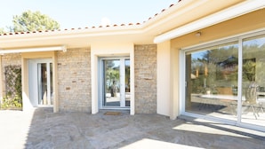 Una casa moderna con patio, pareti in pietra e ampie vetrate.