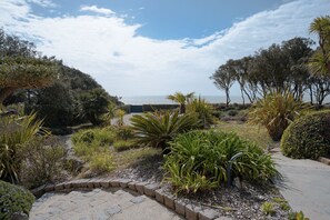 Ein Garten mit unterschiedlichen Pflanzen und einem Weg, der zu einem Blick auf das Meer führt.