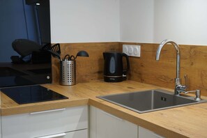 Eine moderne Küche mit integriertem Induktionskochfeld, einer Edelstahl-Spüle und einem Wasserkocher.