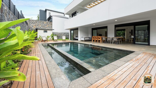 Une maison moderne dotée d’une piscine, de mobilier d’extérieur et d’un mur en pierre.