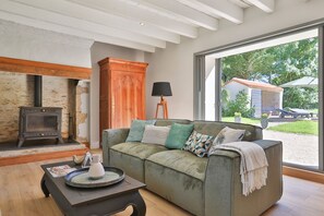 Un salón acogedor con sofá, una mesa de centro, chimenea y vistas al exterior.