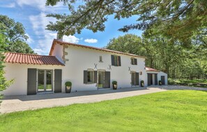 Una casa de dos pisos con techo de tejas, varias ventanas y entrada de grava.