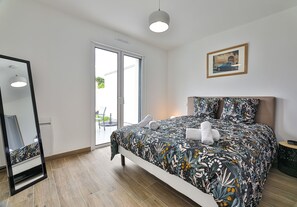 A modern bedroom with a large bed, a mirror, a ceiling light, and a window with a view. - La Marinière des Sables (Les Sables d'Olonne)