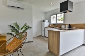 A modern kitchen with a wooden island, white cabinetry, and a built-in microwave. - La Marinière des Sables (Les Sables d'Olonne)
