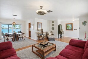 A spacious living room with a dining area, a view of the ocean, and a large chandelier. - Waterfront Villa with Heated Pool & Stunning Sunset Views (Cape Coral)