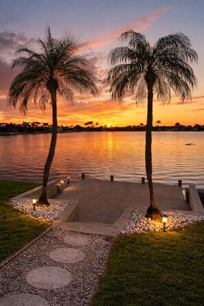 A sunset view with palm trees and a calm lake. - Waterfront Villa with Heated Pool & Stunning Sunset Views (Cape Coral)