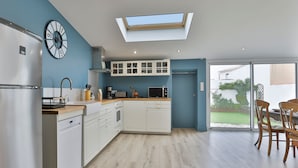Una cucina moderna con finestra a lucernario, mobili bianchi e zona pranzo con sedie in legno.