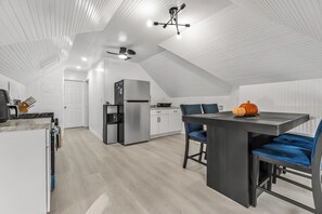 Una cocina moderna con comedor, paredes blancas y techo inclinado.