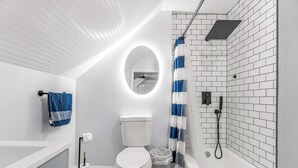 Een moderne badkamer met toilet, wastafel, douche en spiegel.