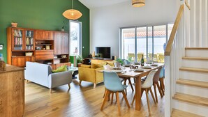 Un salón moderno con comedor, muebles de madera y ventanas grandes.