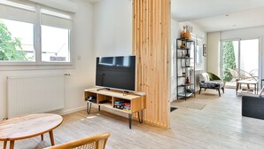 Moderni olohuone, jossa on televisio, puuhuonekaluja ja kirjahylly.