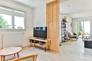 Ein modernes Wohnzimmer mit Fernseher, Holzmöbeln und einem Bücherregal.