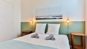 A hotel room with a bed, two bedside tables, a wall-mounted picture, and two wall-mounted lamps. - Maison des Surfeurs - Two Bedroom House, Sleeps 5 (Les Sables d'Olonne)
