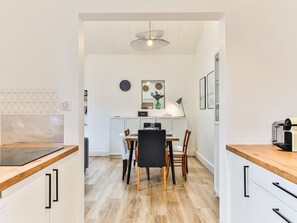 Une cuisine moderne avec un coin repas, des plans de travail en bois et un luminaire au plafond.