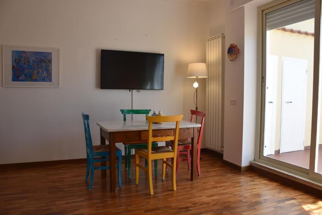 Uma área de refeições com mesa, cadeiras, televisão e janela com vista.