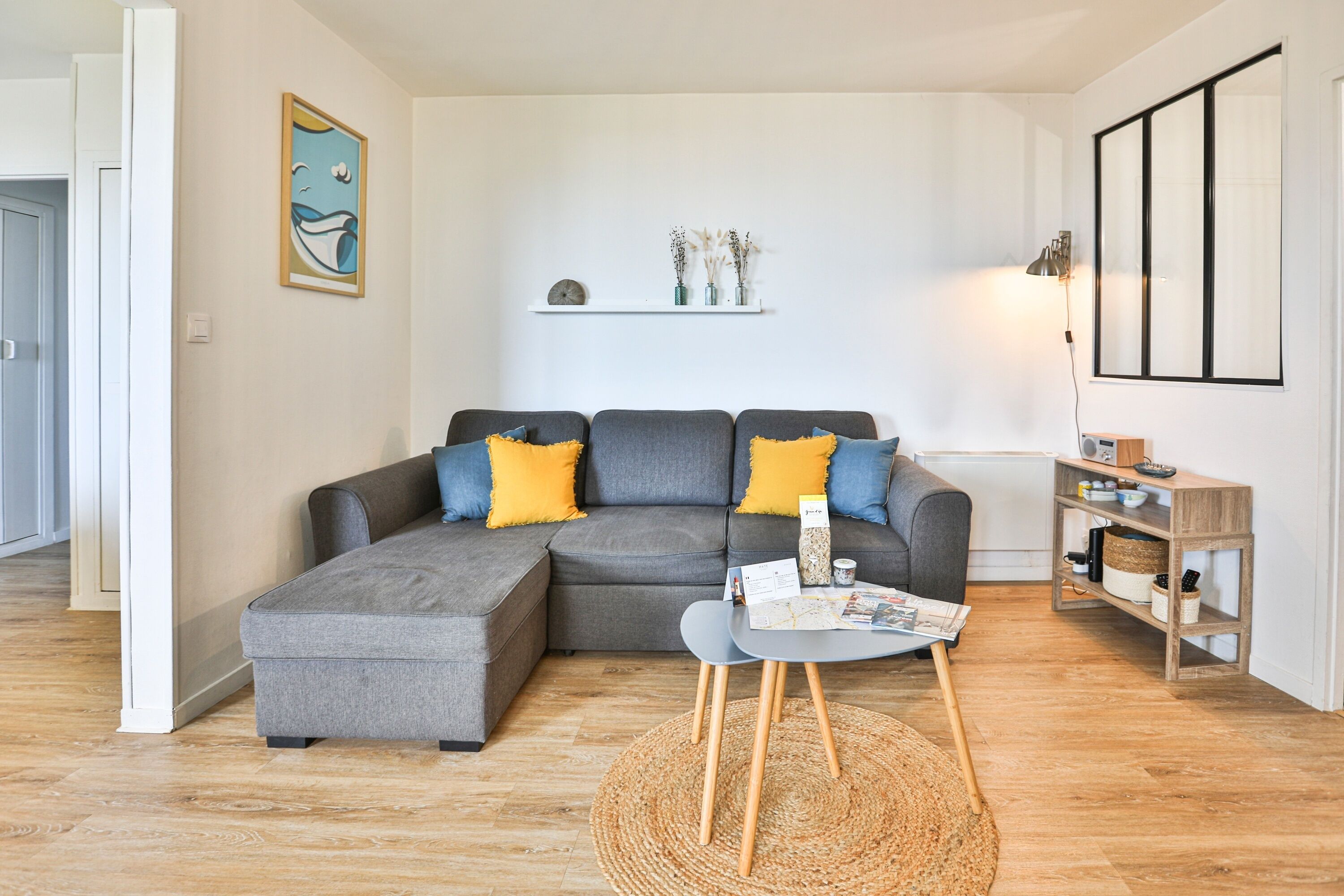 A modern living room with a grey sectional sofa, a small round table, and a bookshelf.