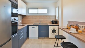 Een moderne keuken met een vaatwasser, oven en wasmachine.