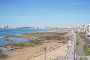 A coastal cityscape with a sandy beach, a promenade, and buildings along the shore. - Cocon Kennedy - sur la baie (Les Sables d'Olonne)