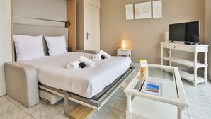 Una habitación de hotel con cama, mesita de noche, televisor y una mesa de centro de vidrio.