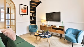 A modern living room with a green sofa, teal armchairs, a coffee table, and a wooden cabinet. - Villa Babil - Four Bedroom House, Sleeps 8 (Les Sables d'Olonne)