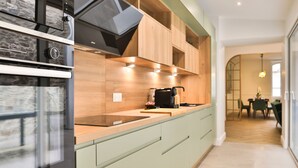 A modern kitchen with a built-in oven, a coffee machine, and light green cabinetry. - Villa Babil - Four Bedroom House, Sleeps 8 (Les Sables d'Olonne)
