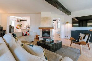Un salon moderne avec une cheminée, un canapé, une table basse et un téléviseur.