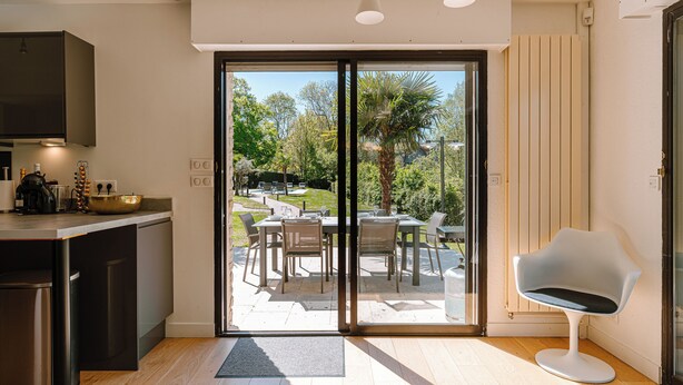 A modern kitchen with a built-in oven, a dining area with a table and chairs, and a sliding glass door leading to an outdoor patio.