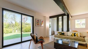 A modern living room with a large sliding glass door, a sofa, a coffee table, and a chair.