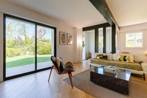 Un salon moderne doté d’une grande porte-fenêtre coulissante, d’un canapé, d’une table basse et d’un fauteuil.