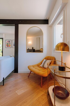 Ein modernes Schlafzimmer mit Bett, Sessel, Nachttisch, Spiegel und Fenster.