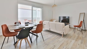 Un soggiorno moderno con tavolo da pranzo, divano, televisione e vista su un balcone.