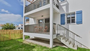 Un edificio di due piani con un balcone, una scala e una recinzione in legno sullo sfondo.