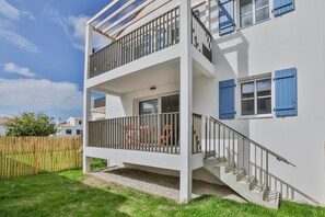 A two-story building with a balcony, a staircase, and a wooden fence in the background. - La Blancharderie - sur l'île de Noirmoutier (Barbâtre)