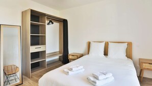 Una camera d'albergo con un letto, un armadio, uno specchio e un comodino.
