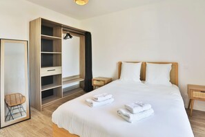 A hotel room with a bed, a wardrobe, a mirror, and a small bedside table. - La Blancharderie - sur l'île de Noirmoutier (Barbâtre)