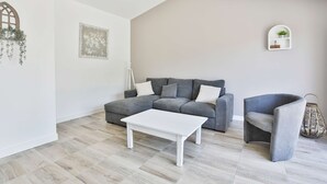En stue med en grå hjørnesofa, et hvidt sofabord og en grå lænestol.