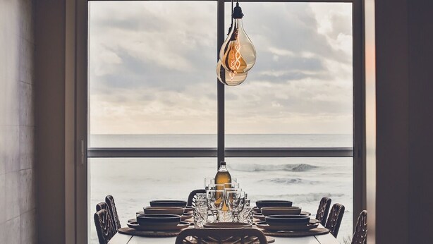 Een eettafel voor zes personen met uitzicht op de oceaan door een groot raam.