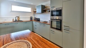 Een moderne keuken met grijze kastjes, een houten aanrechtblad en geïntegreerde apparatuur, waaronder een magnetron en oven.