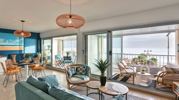 A spacious living area with a sofa, chairs, and a dining table. There is a balcony with a view of the sea. - Les Loges du Remblai - vue imprenable sur la baie (Les Sables d'Olonne)