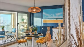 A dining area with a table, chairs, and a hanging light fixture. - Les Loges du Remblai - vue imprenable sur la baie (Les Sables d'Olonne)