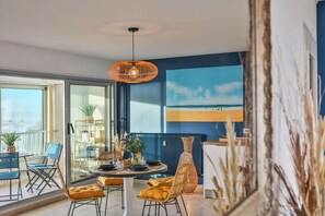 A dining area with a table, chairs, and a hanging light fixture. - Les Loges du Remblai - vue imprenable sur la baie (Les Sables d'Olonne)