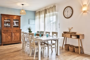 Ein Essbereich mit Holztisch, weißen Stühlen, einem Holzschrank und einer Wanduhr.