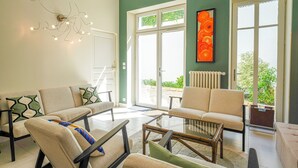 Uma sala de estar moderna com sofá, poltronas, mesa de centro de vidro e um lustre de parede exclusivo.